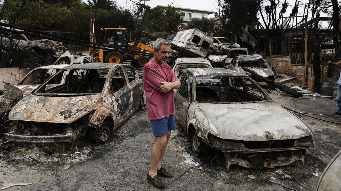 Mati, 2018. július 24.Kiégett autóroncsok között egy férfi az Athéntól keletre fekvő Matiban 2018. július 24-én. A görög főváros közelében keletkezett két erdőtűz legalább hatvan ember halálát okozta, valamint házakat és autókat is elpusztított. (MTI/EPA/Jánisz Koleszidisz)