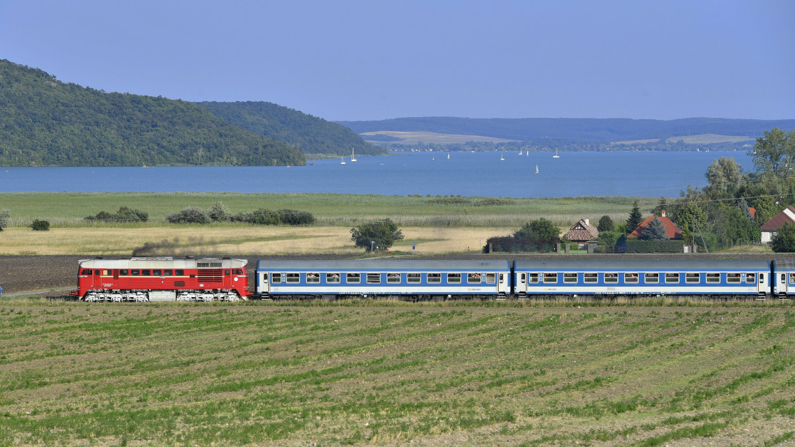 A hatvanas évek stílusában lefestett M62-es Szergej elnevezésű mozdony vontatja a Tekergő nevű menetrend szerinti gyorsvonatot a Balaton északi partján, Aszófőnél 2018. július 29-én.