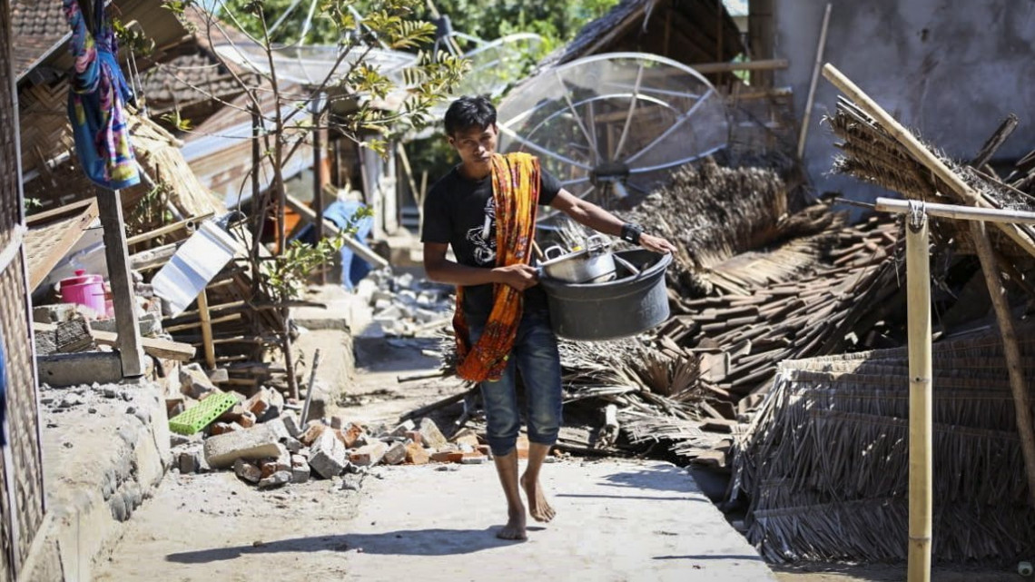 Nyugat-Nusa Tenggara, 2018. augusztus 6.Használható holmikkal a kezében megy egy férfi lakóházak romjai között az indonéziai Lombok szigetén levő Nyugat-Nusa Tenggara tartományban 2018. augusztus 6-án. Az előző napi 7-es erősségű földmozgásban, amelynek epicentrumát Lombok-szigeten mérték 10,5 kilométeres mélységben, legkevesebb 142 ember életét vesztette. (MTI/EPA)