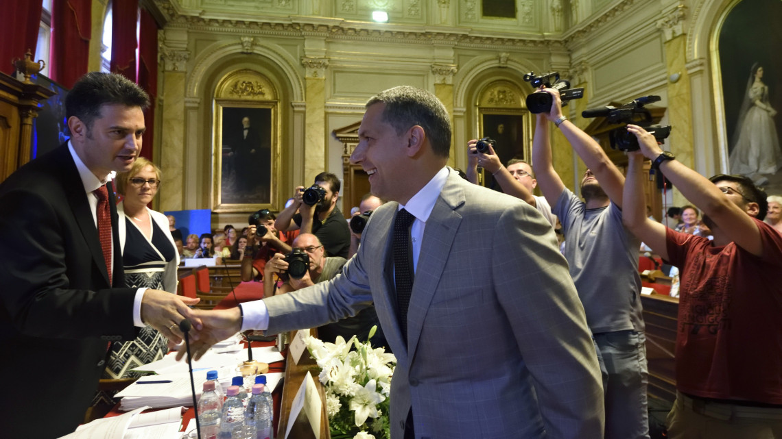 Márki-Zay Péter (független) polgármester (b) és Lázár János, a térség fideszes országgyűlési képviselője kezet fog a hódmezővásárhelyi közgyűlés ülésén 2018. május 29-én.