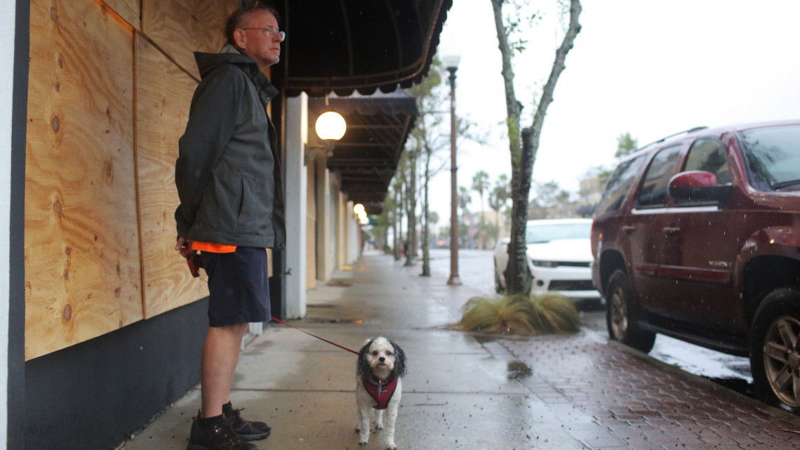 Panama City, 2018. október 10.Bedeszkázott kirakatok előtt áll egy férfi kutyájával a floridai Panama Cityben 2018. október 10-én, a Michael névre keresztelt hurrikán érkezése előtt. Az államban szükségállapotot rendeltek el a közelgő trópusi vihar miatt. (MTI/EPA/Dan Anderson)