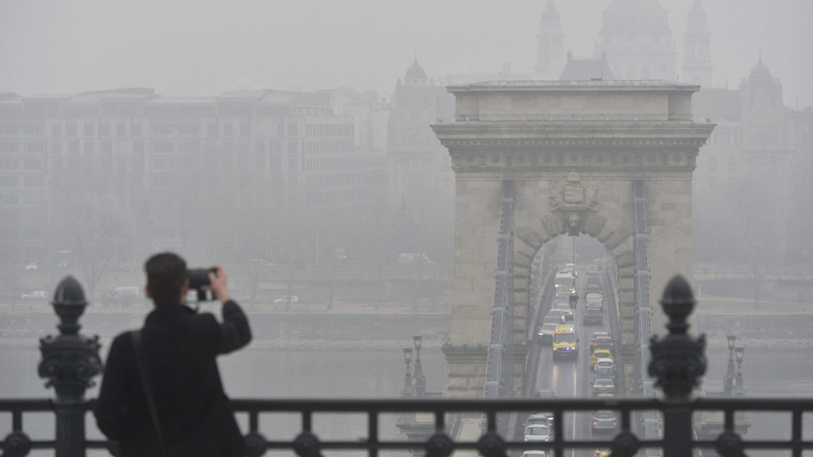 Egy turista fényképez a szmogos, ködös időben a Lánchíd budai hídfője közelében 2017. február 15-én. Budapesten ismét elrendelte Tarlós István főpolgármester a szmogriadó tájékoztatási fokozatát, miután a mérőállomásokon a szálló por légszennyezettségi szintje február 13-án három, 14-én pedig négy mérőponton meghaladta a tájékoztatási küszöbértéket.