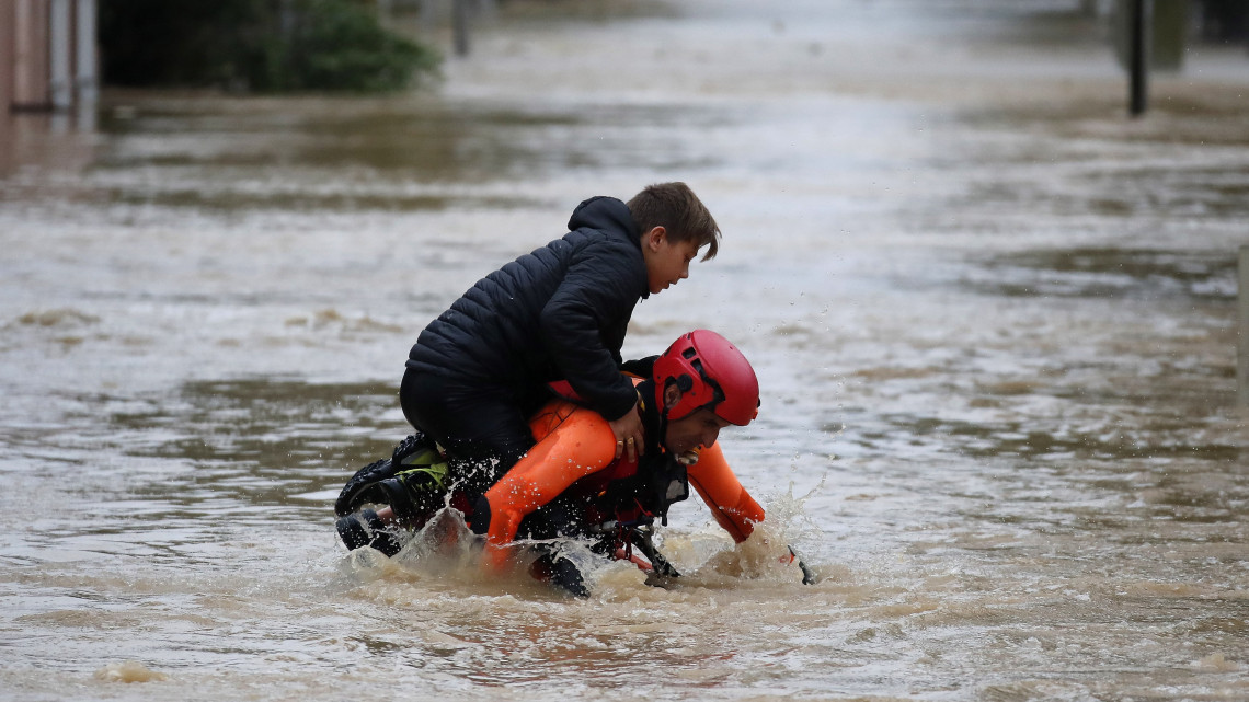 Trebes, 2018. október 15.A lakosok kimenekítését végző francia tűzoltók egyike egy fiút visz a hátán egy vízzel elárasztott utcán a dél-franciaországi Trebes városban 2018. október 15-én, miután az éjszaka folyamán néhány óra leforgása alatt több havi csapadékmennyiség zúdult a térségre. A Franciaország déli részét sújtó áradásokban legalább hatan életüket vesztették. (MTI/EPA/Guillaume Horcajuelo)