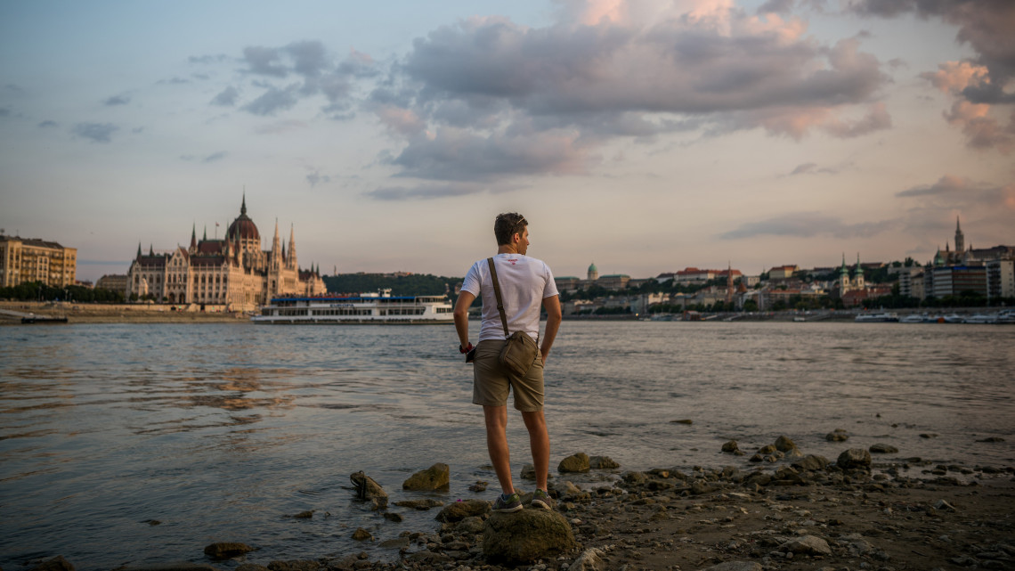 Érdeklődő a Duna partján a budapesti Margit-sziget alacsony vízállásnál járható déli szigetcsúcsánál, a Margit híd középső pillérjénél 2018. augusztus 16-án.
