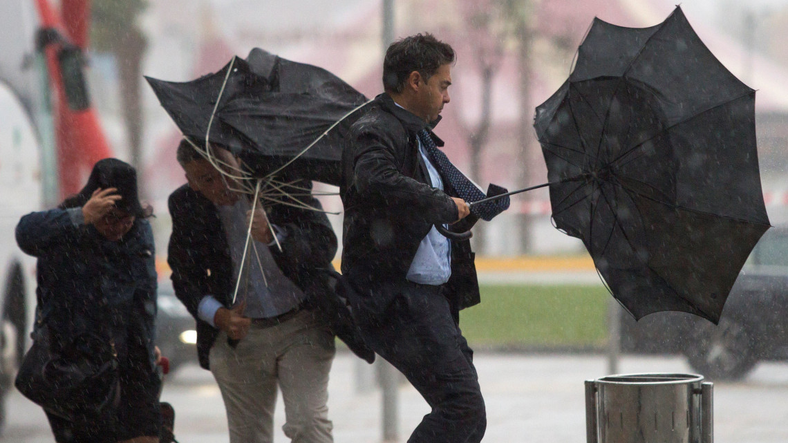 Járókelők az erős szél miatt kifordult esernyővel a kezükben a dél-spanyolországi Málagában 2018. október 18-án. A spanyol hatóságok narancssárga riasztást adtak ki a Földközi-tenger térségében a hatalmas esőzések miatt. Egy négyzetméternyi területre, akár 60 liternyi csapadék hullhat óránként.