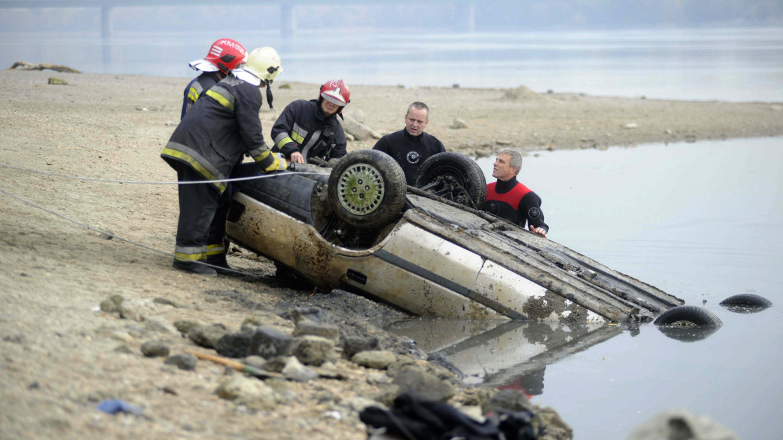 Tűzoltók a partra vontatnak egy személygépkocsit Budapesten, a XXII. kerületben 2018. október 19-én. A korábban a folyóba került autó a rekord alacsony vízállás miatt látszott ki a folyóból.