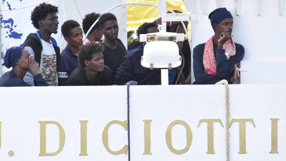 Catania, 2018. augusztus 23.Illegális bevándorlók várakoznak az olasz parti őrség Diciotti hajójának fedélzetén Catania kikötőjében 2018. augusztus 23-án. Az Európába igyekvő és Málta környékén a Földközi-tengerből kiemelt 177 migráns partra szállását nem engedélyezi Matteo Salvini olasz belügyminiszter, hacsak nem kap garanciát az Európai Uniótól, hogy az utasokat szétosztják a tagállamokban. (MTI/EPA/Orietta Scardino)