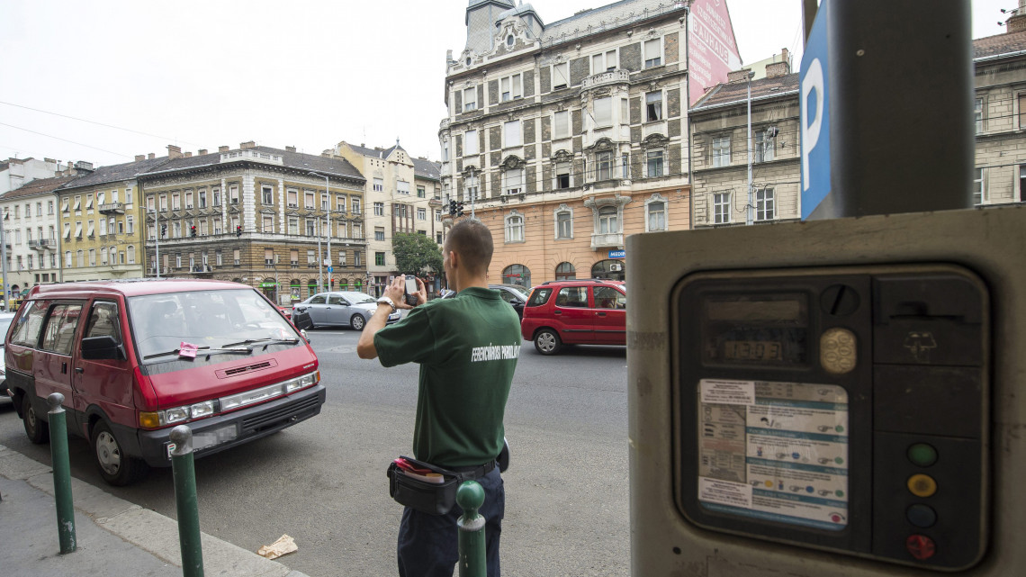 Vörös Egon, a Ferencvárosi Parkolási Kft. ellenőre egy szabálytalanul parkoló autót fényképez le a büntetés kiszabása után a főváros IX. kerületében 2013. augusztus 21-én.