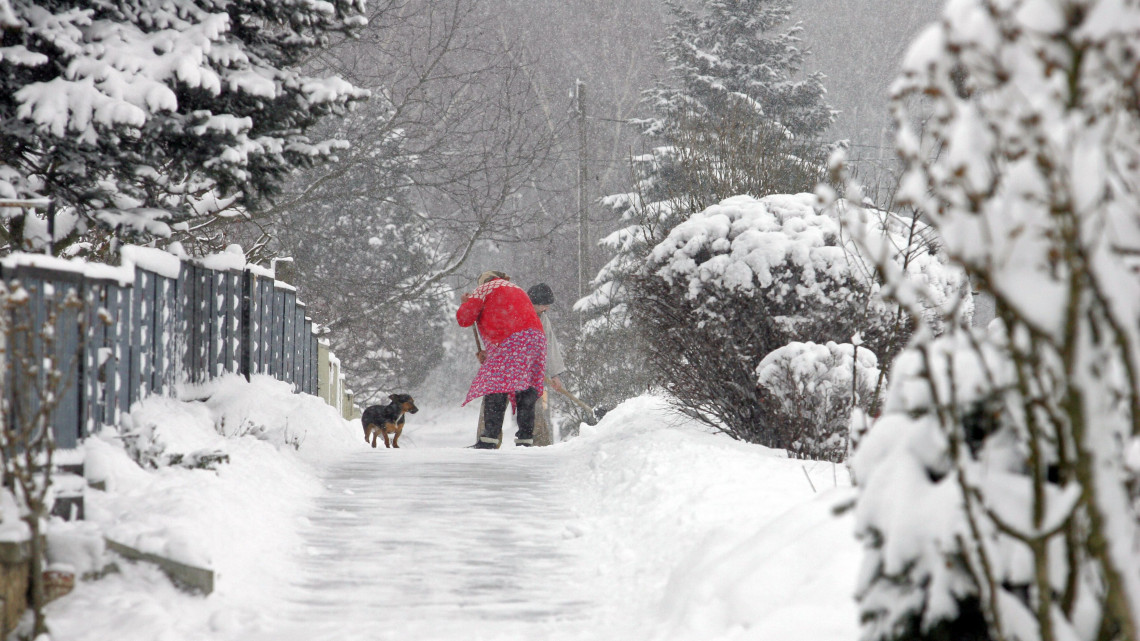 A járdát tisztítják a lakók a Somogy megyei Lengyeltóti egyik utcájában. A térségben folyamatosan havazik, egy nap alatt több mint 20 centiméter vastagságú hó hullott.