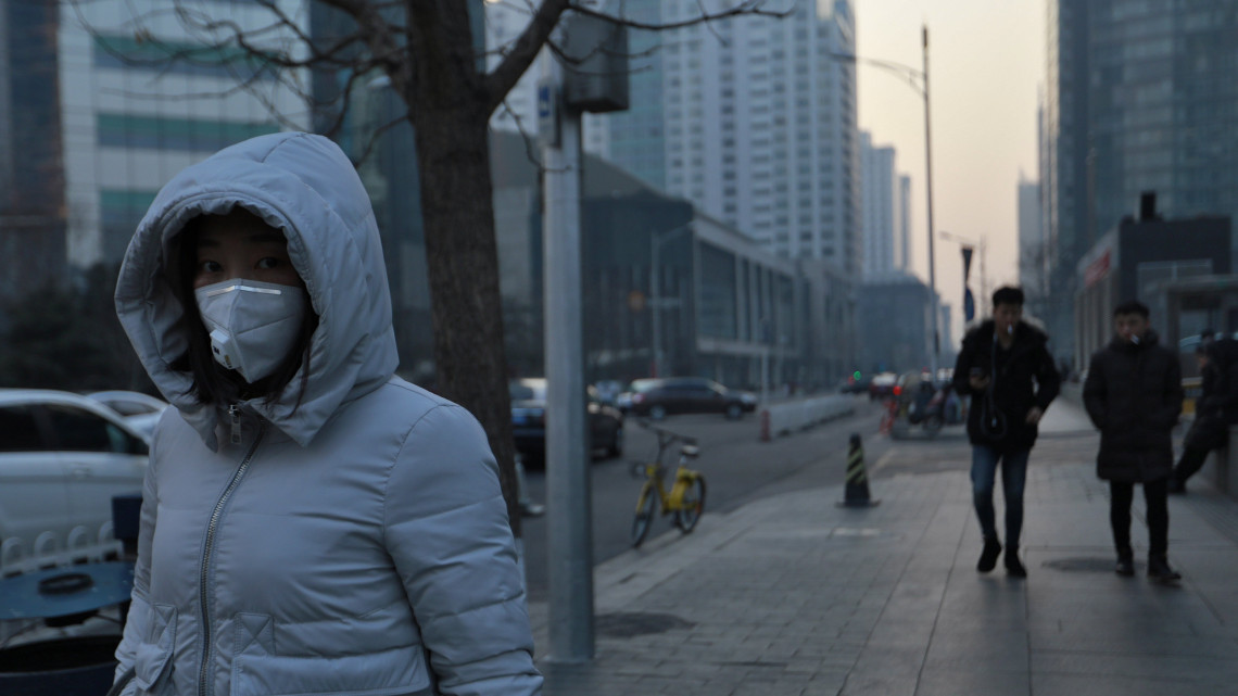 Peking, 2018. január 13.A levegő szennyezettsége ellen védekezik maszkkal egy járókelő Pekingben 2018. január 13-án. A füstköd miatt a pekingi hatóság a második legmagasabb fokozatú, narancssárga színű riasztási fokozatot rendelték el, ami a nehézipari üzemek működésének korlátozását jelenti. (MTI/EPA/Hoou Hvi Jung)