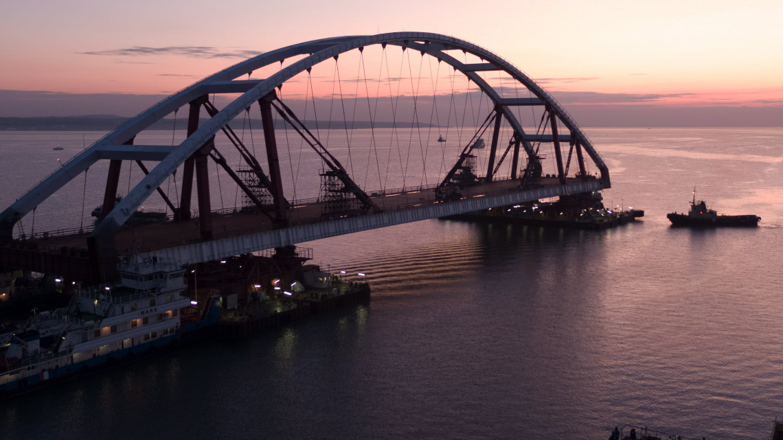 Kercsi-szoros, 2017. október 11.A Krími híd (vagy Kercsi híd) projektjének információs központja által közreadott képen az épülő híd egyik íves főtartóját szállítják beépítésre a Fekete-tengert az Azovi-tengertől elválasztó Kercsi-szorosban, a vitatott hovatartozású Krím-félszigetnél 2017. október 10-én. A két, egyenként 227 méter hosszú ívelt főtartó 6000 tonna összsúlyú vasúti sínnel és mintegy 1000 tonna közúti aszfaltburkolattal terhelt felszerkezetet tart majd a vízfelszín felett 35 méterrel. A 19 kilométeres kombinált hídpálya a Krím-félszigetet köti majd össze a kontinentális Oroszországgal, a tervek szerint 2018 végétől. (MTI/EPA/Krími híd projektjének információs központja)