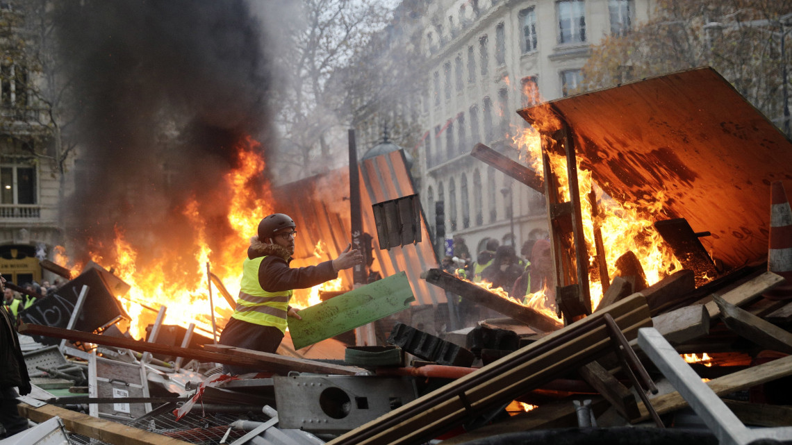 Úttorlasz tüzét táplálja egy láthatósági mellényt viselő tiltakozó az üzemanyagadó tervezett emelését ellenző tüntetésen Párizsban 2018. november 24-én. Országszerte csaknem 81 ezren vonultak utcákra békés tüntetéseken, a fővárosban 8 ezren tiltakoztak az erőszakossá fajult megmozduláson.