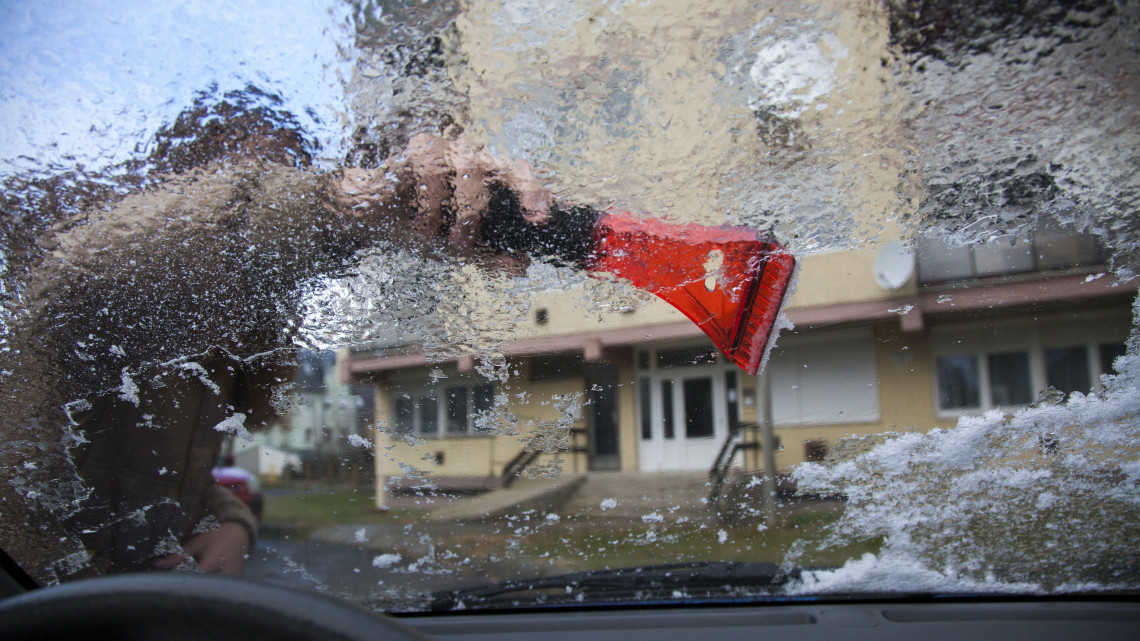 Egy autó ónos esőtől eljegesedett szélvédőjét tisztítják Nagykanizsán 2016. december 14-én.