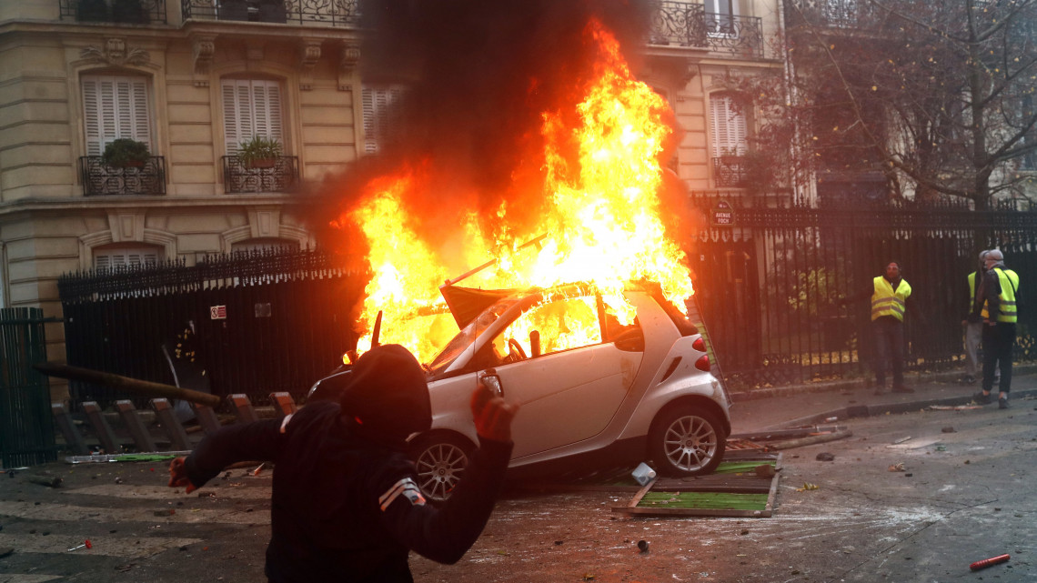 A dráguló üzemanyagárak ellen tiltakozó sárga láthatósági mellényt viselő tüntetők által felgyújtott autó ég Párizsban 2018. december 1-jén. A sárgamellényeseknek ez a harmadik nagy tüntetése, november 17. óta tartanak demonstrációkat különböző helyszíneken az ország útjain.