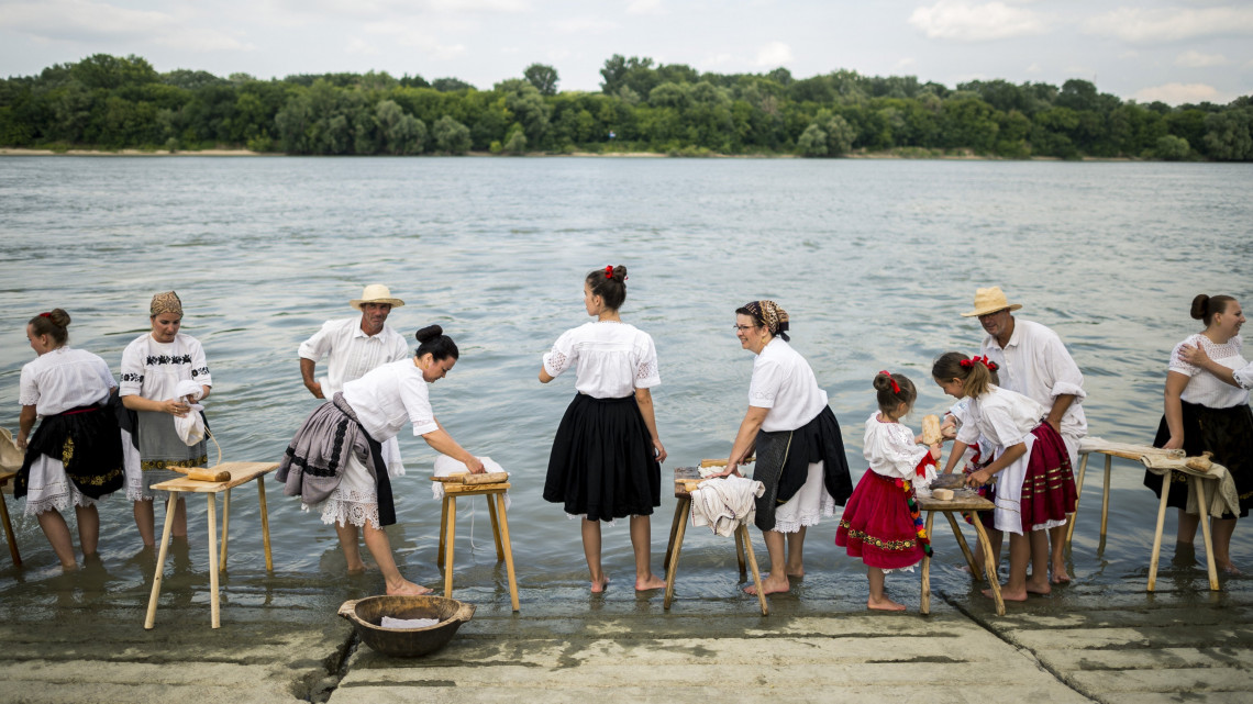 Sokác népviseletbe öltözött résztvevők hagyományos eszközökkel ruhát mosnak a Duna partján a Mohácsi Sokacok Olvasókörének 10. Pranje na Dunavu - Dunai Mosás című rendezvényén tartott bemutatón Mohácson 2018. július 7-én.