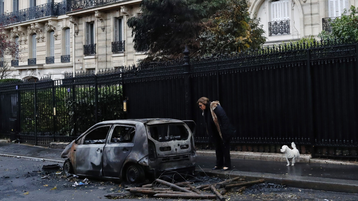 Kiégett autót néz meg egy járőkelő a Diadalív közelében, Párizsban 2018. december 2-án, a dráguló üzemanyagárak ellen tiltakozó sárgamellényesek zavargásba torkolló tüntetése utáni napon. Párizs belvárosának legelegánsabb részében a tüntetők autókat gyújtottak fel, épületeket rongáltak meg, kirakatokat fosztottak ki és utcakövekből emeltek barikádokat.