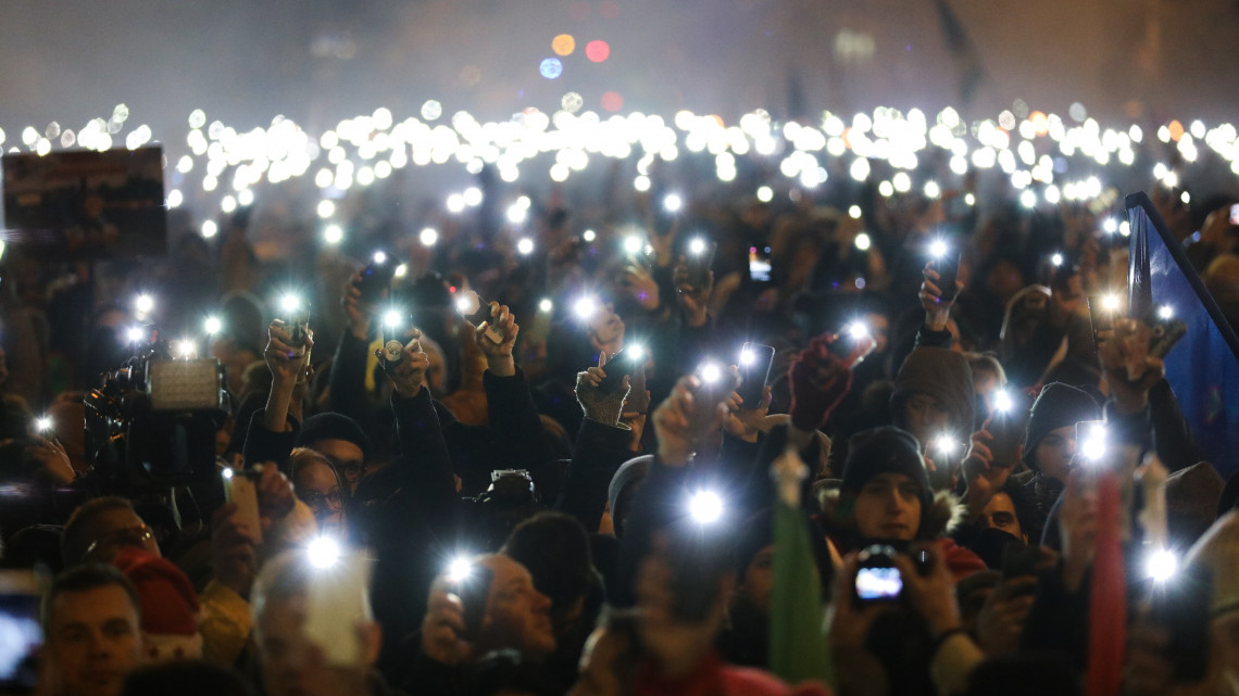 Telefonjaikkal világítanak a Boldog karácsonyt, miniszterelnök úr! címmel meghirdetett kormányellenes demonstráció résztvevői a belvárosi Alkotmány utcában 2018. december 16-án.