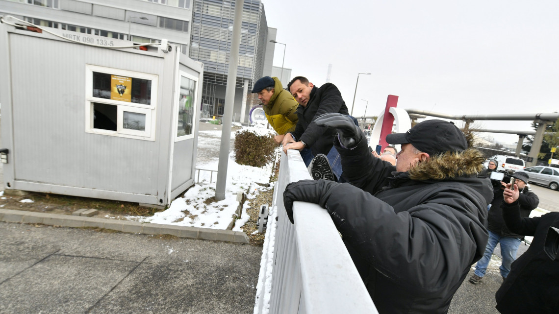 Korózs Lajos (elöl) és Molnár Zsolt MSZP-s országgyűlési képviselők átmásznak a kerítésen az MTVA Kunigunda utcai székházának területére 2018. december 17-én. Ellenzéki képviselők az önkéntes túlmunka idő bővítéséről szóló törvény ellen demonstrálnak az MTVA székháza előtt és élő adásban szeretnék elmondani nyilatkozatukat.