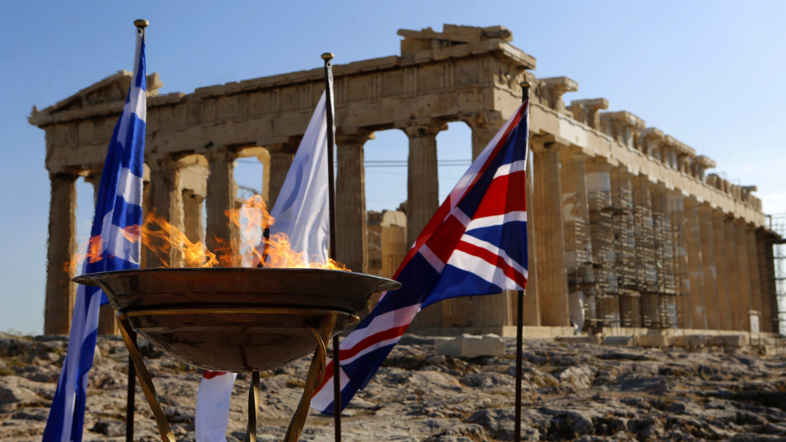 Athén, 2012. május 16.Az olimpiai láng ég egy kandelláberben, az athéni Akropoliszon, a Parthenon előtt, miután a lángot vivő staféta a görög fővárosba érkezett. A lángot május 17-én adják át a 2012-es londoni nyári olimpia küldöttségének. A láng mögött a görög az olimpiai és a brit zászló (b-j) látható. (MTI/EPA/Jannisz Behrakisz)