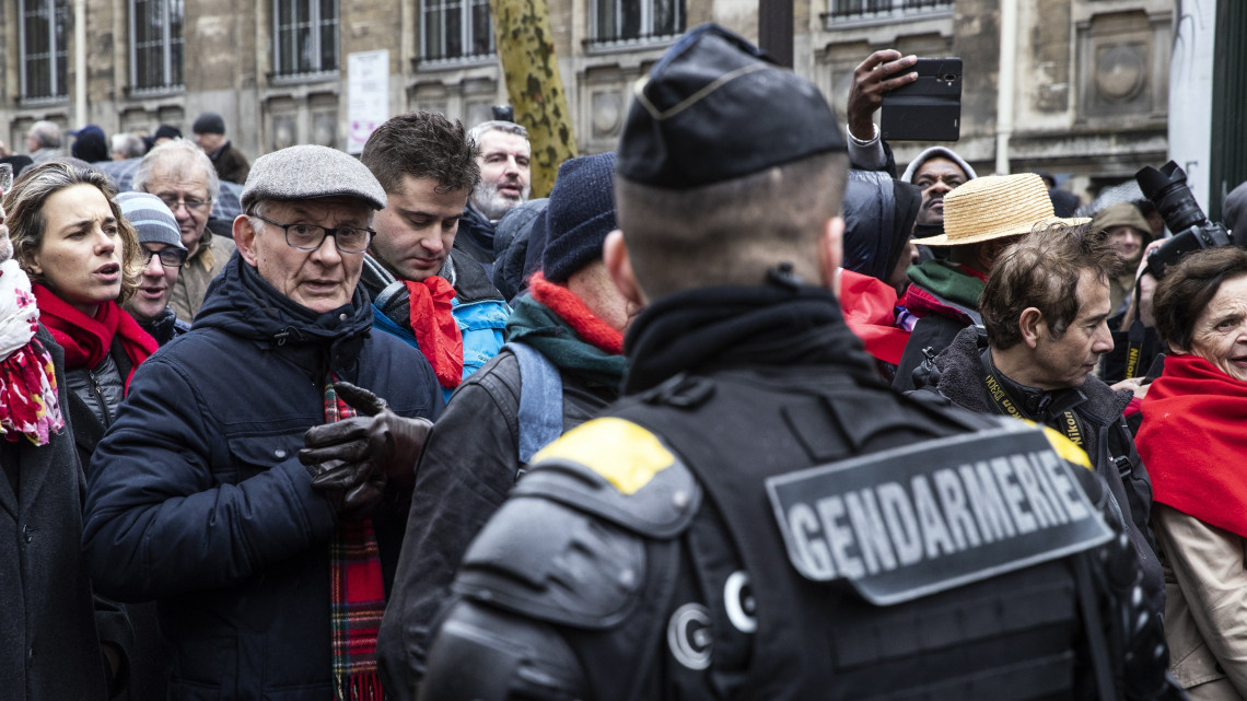  A sárgamellényes mozgalom követeléseit elutasító és a francia kormányt támogató vörös nyaksálat viselő tüntetők felvonulást tartanak Párizsban 2019. január 27-én.