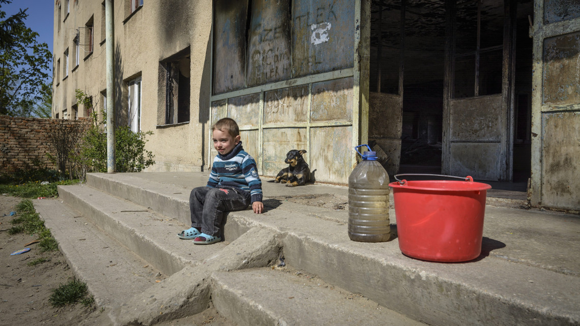 Kisfiú ül egy lépcsőn egy romos társasháznál Beregszászon, ahova adományokat szállított a Magyar Református Szeretetszolgálat 2015. április 23-án. A segélyszervezet 2014 szeptemberében kezdődött programja keretében hetente alapvető élelmiszereket, egészségügyi felszereléseket és ruhákat szállítanak kárpátaljai rászorulóknak.