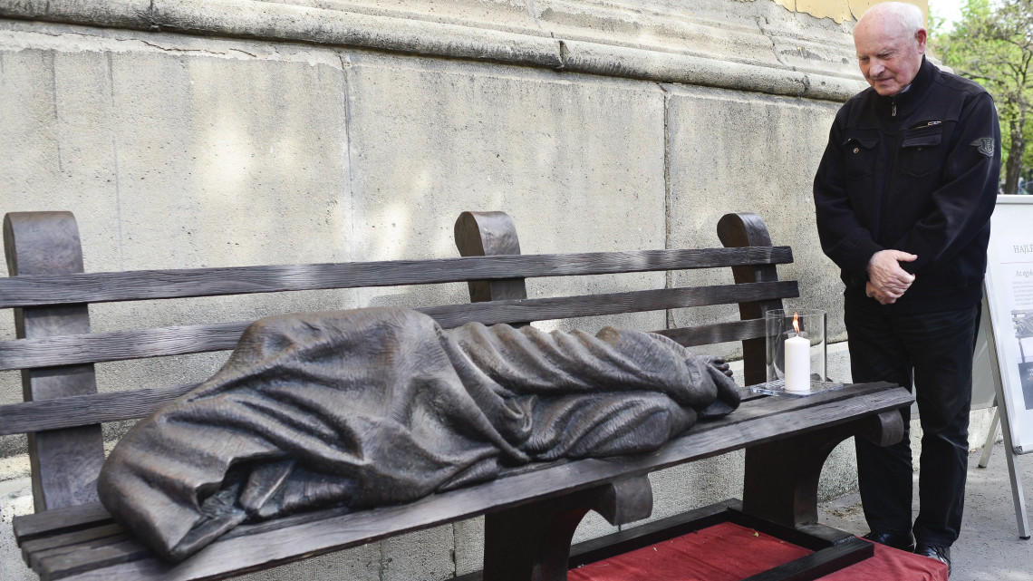 Kozma Imre, a Betegápoló Irgalmasrend vezetője a Hajléktalan Jézus szobra mellett a VIII. kerületi Horváth Mihály téren az alkotás átadásán 2017. április 11-én. A Jézust padon fekvő hajléktalanként megjelenítő Krisztus-ábrázolás Timothy Schmalz kanadai szobrász alkotása, első példányát 2013-ban helyezték el Torontóban. A szobor egy-egy példányát azóta több nagyvárosban is elhelyezték.
