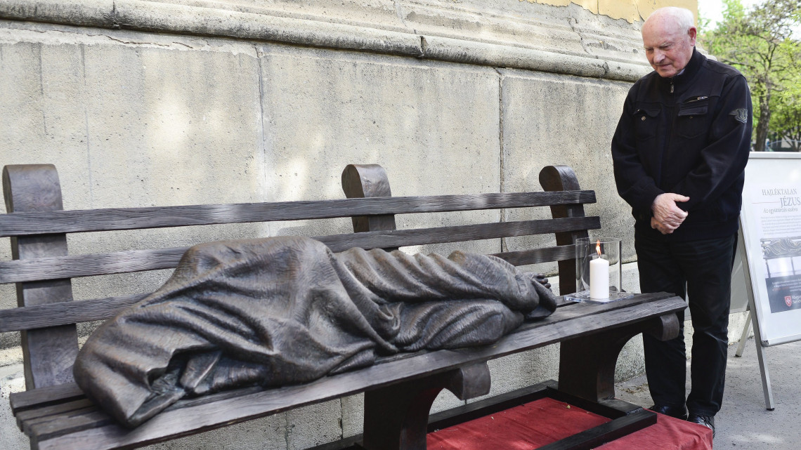 Kozma Imre, a Betegápoló Irgalmasrend vezetője a Hajléktalan Jézus szobra mellett a VIII. kerületi Horváth Mihály téren az alkotás átadásán 2017. április 11-én. A Jézust padon fekvő hajléktalanként megjelenítő Krisztus-ábrázolás Timothy Schmalz kanadai szobrász alkotása, első példányát 2013-ban helyezték el Torontóban. A szobor egy-egy példányát azóta több nagyvárosban is elhelyezték.