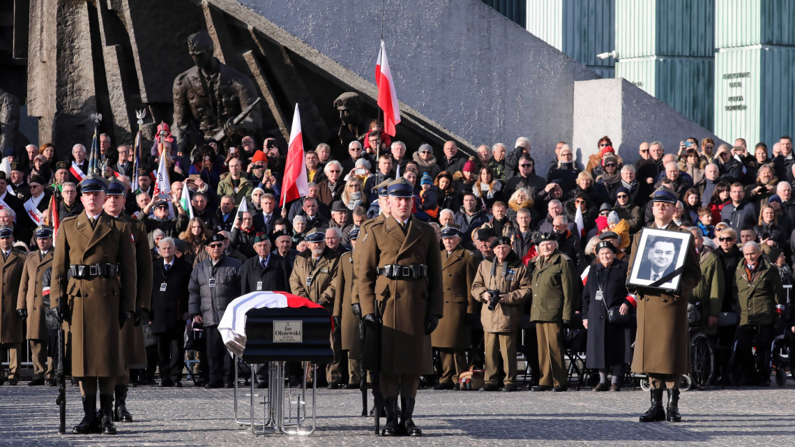 Jan Olszewski egykori lengyel miniszterelnök portréját tartja egy katona a zászlóval letakart koporsó mellett a néhai politikus végső nyughelyére, a varsói Powazki katonai temetőbe tartó gyászmenet állomásán, az 1944-es varsói felkelés emlékművénél 2019. február 16-án. A totalitarizmusok elleni harc jeles alakja február 7-én, nyolcvannyolc éves korában hunyt el.