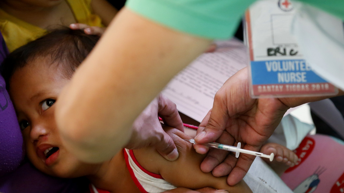 Kanyaró elleni védőoltást ad be egy Fülöp-szigeteki gyereknek egy otthonlátogató védőnő Manila szegénynegyedében 2019. február 16-án. A cseppfertőzéssel terjedő betegség az utóbbi hetekben mintegy hatvan ember halálát okozta Luzon szigetén és a Visayan-szigeteken, az áldozatok többsége négyéves kor alatti gyermek.