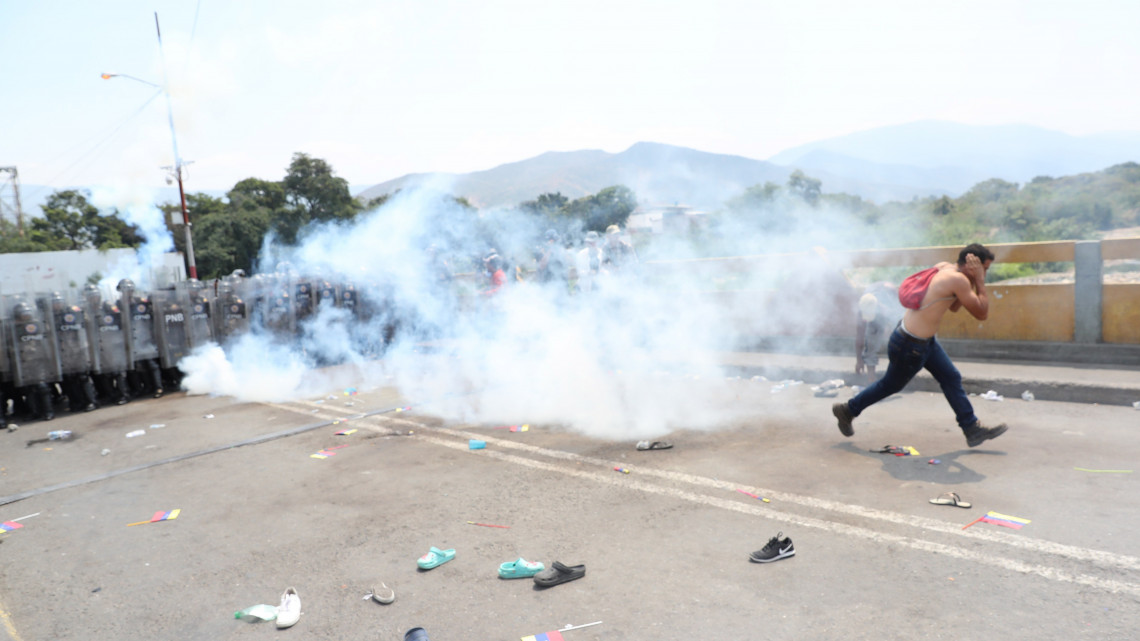 Venezuelai rendőrök könnygázt vetnek be a Simón Bolívar híd lezárása miatt tiltakozó tüntetők ellen a venezuelai-kolumbiai határon lévő Cúcutában 2019. február 23-án. Nicolás Maduro venezuelai elnök előző nap rendelte el a Kolumbiával közös határ egyes átkelőinek lezárását, hogy megakadályozza az Egyesült Államokból érkező segélyszállítmány bejuttatását az országba. Venezuelában hatalmi harc zajlik Maduro és a magát ideiglenes elnökké nyilvánító Juan Guaidó parlamenti elnök között. Guaidó, aki január 23-án kikiáltotta magát Venezuela ideiglenes elnökének, az Egyesült Államok és több más nyugati ország támogatását élvezi.