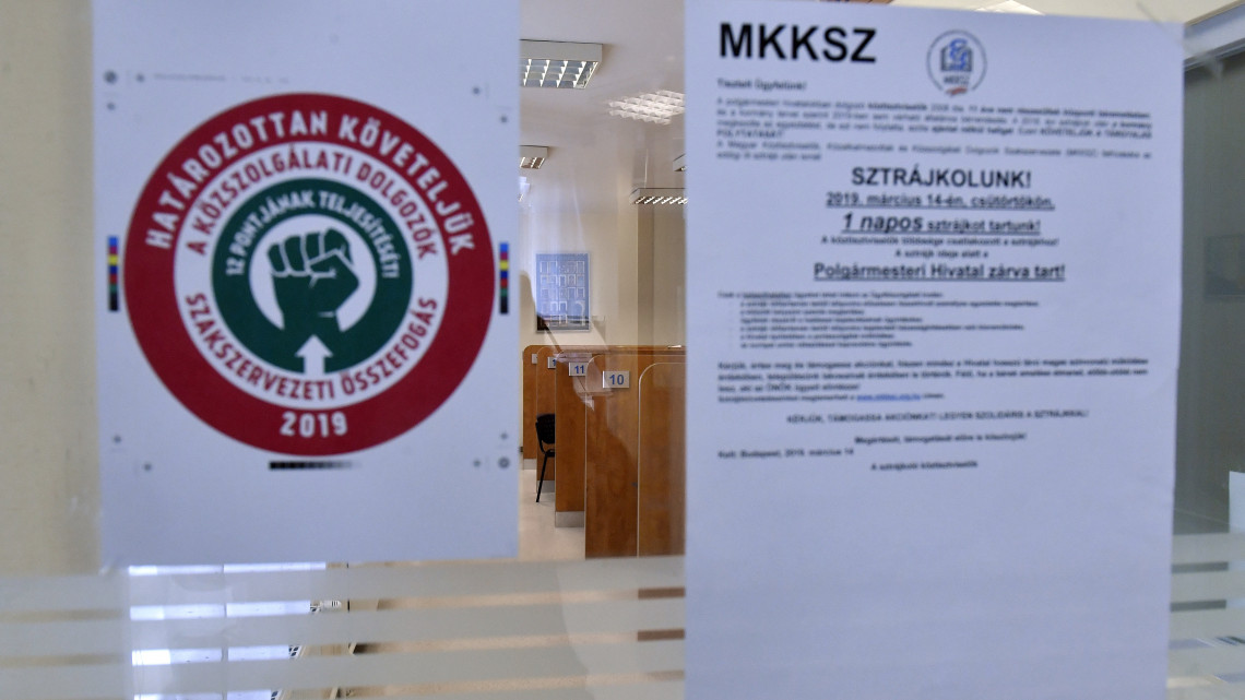Feliratok a Magyar Köztisztviselők, Közalkalmazottak és Közszolgálati Dolgozók Szakszervezete (MKKSZ) egynapos sztrájkja alatt a XV. kerületi polgármesteri hivatal ajtaján 2019. március 14-én.