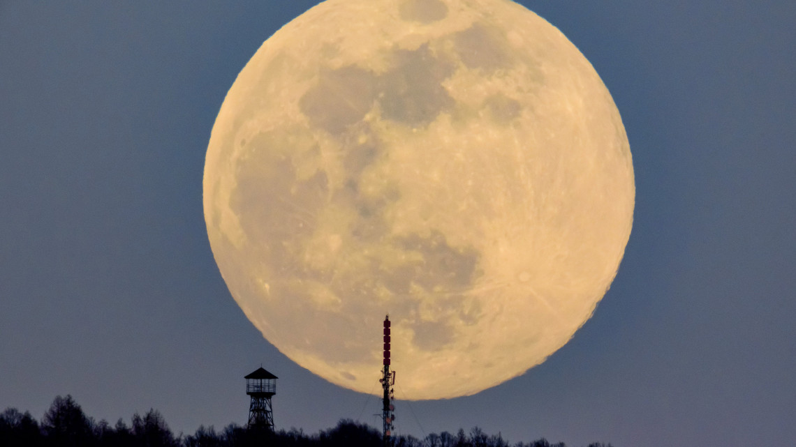 A felkelő Hold látszik a Karancs csúcsán lévő kilátó és az Antenna Hungária adótornya mögött Karancskeszi közeléből fotózva 2019. március 20-án.