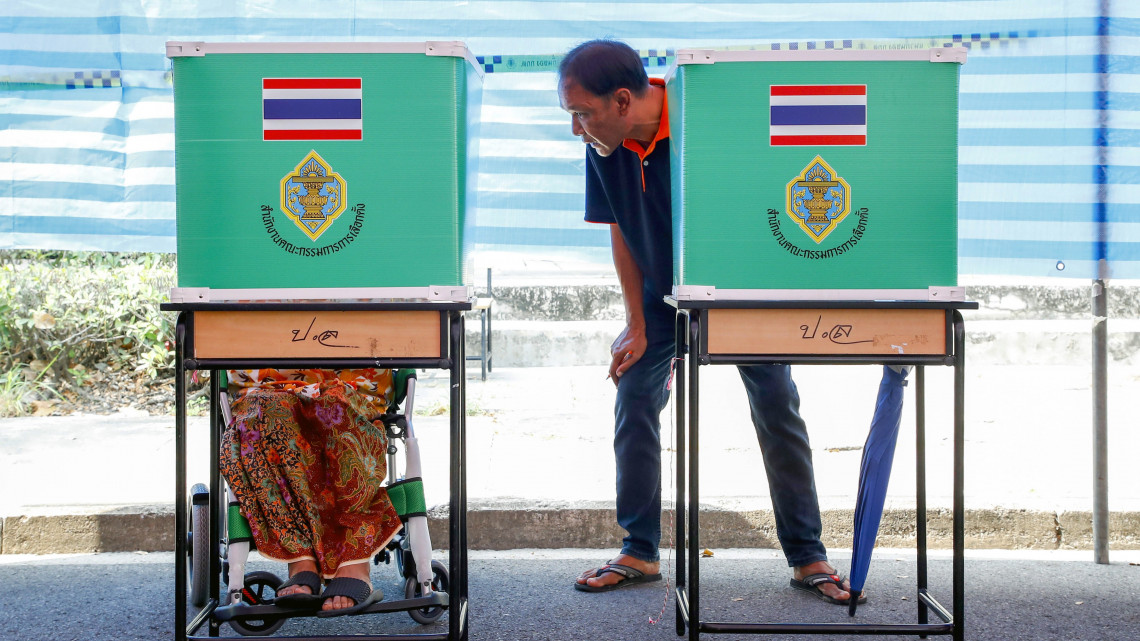Keresszékes asszonynak ajánlja fel segítségét egy férfi egy bangkoki szavazóhelyiségben a thaiföldi parlamenti választásokon 2019. március 24-én. A 2014 májusa óta tartó katonai uralom kezdete óta először tartanak parlamenti választást a délkelet-ázsiai országban.