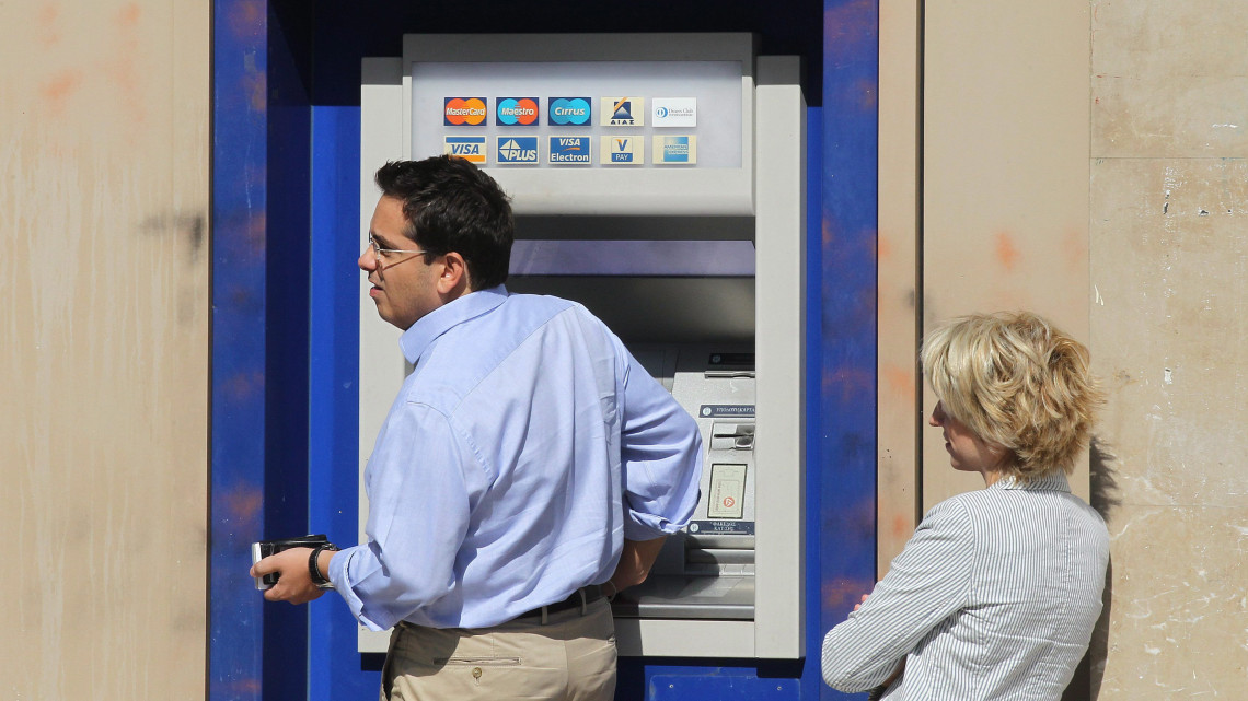 Athén, 2011. szeptember 23.Az EFG Eurobank Ergasias egyik utcai bankjegykiadó automatájából vesz fel pénzt egy férfi a görög fővárosban, Athénban. A Moodys nemzetközi hitelminősítő egyszerre két fokozattal leminősített nyolc görög bankot többek között azzal az indokkal, hogy az emberek kivonják a megtakarításokat a betéteikből, a pénzintézetek pedig egyre függőbb helyzetbe kerülnek az Európai Központi Bank hiteltámogatásától, miközben tovább romlik a gazdasági környezet az adósságválsággal küzdő Görögországban. (MTI/EPA/Oresztisz Panajotu)