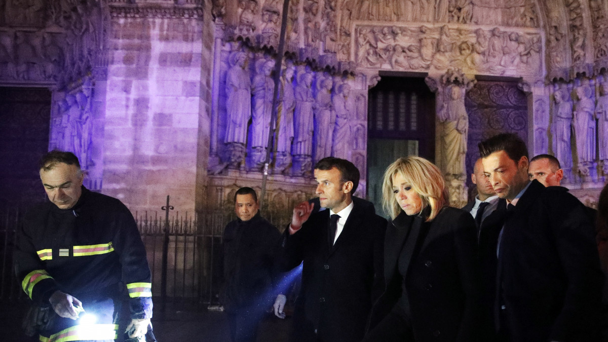 Emmanuel Macron francia elnök (k) és felesége, Brigitte Macron látogatást tesz a kigyulladt Notre Dame székesegyházban 2019. április 15-én. Macron kijelentette, hogy újjáépítik a Notre Dame-ot. Hangsúlyozta, hogy a tűzoltók bátorságának köszönhetően a székesegyház homlokzata és két fő tornya nem dőlt le. Az első hírek szerint a lángok a restaurálási munkálatokhoz felállított állványzaton, a tetőszerkezetnél keletkeztek, és onnan terjedtek tovább. A tűz következtében összeomlott az épület huszártornya és odaveszett teljes tetőszerkezete.