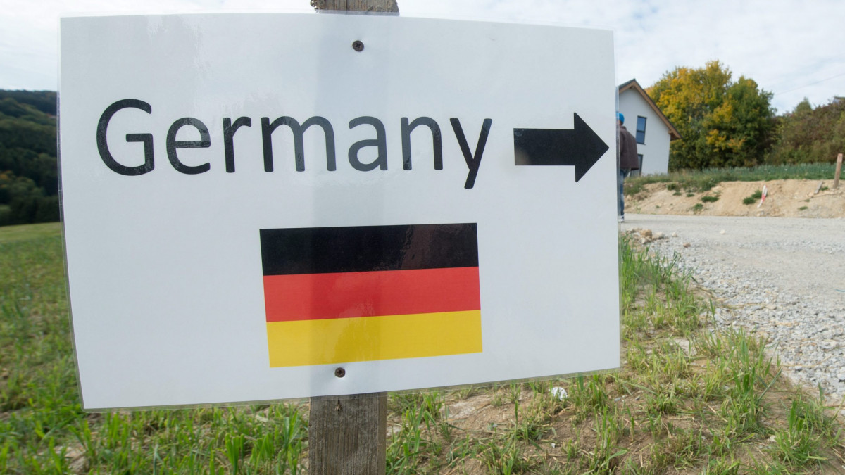 Julbach, 2015. október 6.Szíriai bevándorlók egy Németország jelentésű felirattal ellátott, rögtönzött útjelző tábla mellett mennek el a dél-németországi Julbachban, az osztrák határ közelében 2015. október 6-án. (MTI/EPA/Armin Weigel)