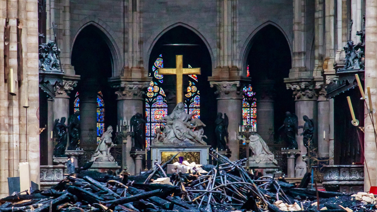 Üszkös romok a leégett tetőszerkezetű párizsi Notre-Dame-székesegyház belsejében 2019. április 16-án. A lángok előző nap a restaurálási munkálatokhoz felállított állványzaton keletkeztek, és onnan terjedtek tovább. A tűz következtében összeomlott az épület huszártornya és odaveszett a teljes tetőszerkezete.