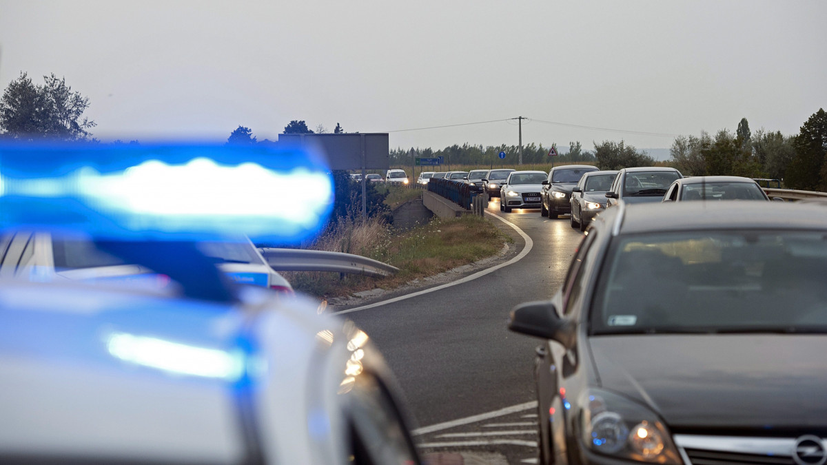 Forgalmi dugó az M1 autópálya feletti átvezető hídon Tata határában 2013. augusztus 9-én. Egy Győr felé haladó kamion átszakította az M1-es két pályáját elválasztó szalagkorlátot, áttért a szemben lévő sávba, majd ott fejtetőre állt. A járműbe belerohant egy Budapest felé haladó kisebb tehergépkocsi, egy másik sofőr pedig a kormányát elrántva az árokba hajtott. A balesetben a teherautók vezetői sérültek meg, őket kórházba szállították. A háttérben villámlás.