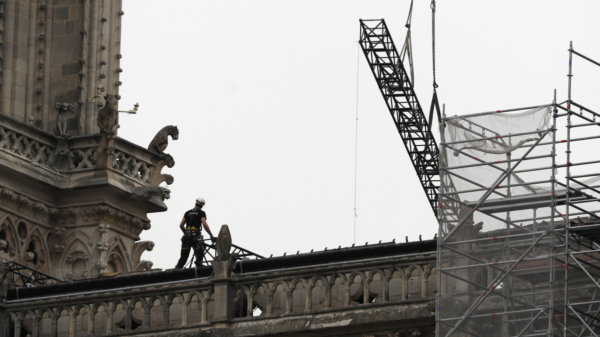 Munkások a párizsi Notre-Dame-székesegyházon 2019. április 23-án. Ipari alpinisták ponyvával borítják be a leégett tető helyét, hogy megóvják a templombelsőt az esőtől. Nyolc nappal korábban lángok csaptak fel a restaurálási munkálatokhoz felállított állványzaton, a tűz következtében összeomlott az épület huszártornya és odaveszett a teljes tetőszerkezete.