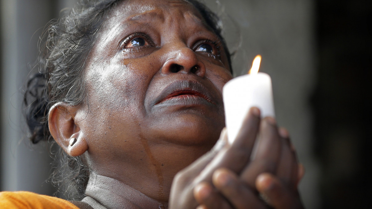 Könnyezve imádkozik égő gyertyával a kezében egy asszony a Sri Lanka-i merényletek áldozataiért tartott háromperces megemlékezésen Colombóban 2019. április 23-án. A Srí Lanka-i hatóságok szerint a terrortámadásokat a Nemzeti Tauhít Dzsamaat nevű iszlamista szélsőséges csoport követte el húsvétvasárnap. A nyolc robbantásos merényletben legkevesebb 321-en életüket vesztették, és 521-an megsebesültek.