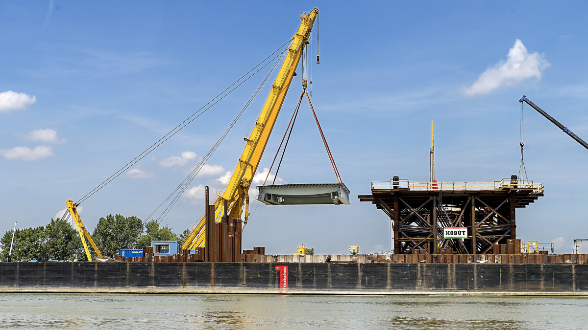 Beemelik az első acélelemet az új komáromi Duna-híd építkezésén 2018. június 11-én. A híd első három elemét emelték a helyére, az egyenként 165 tonnás alkotórészek Csepelről a Dunán érkeztek a helyszínre.