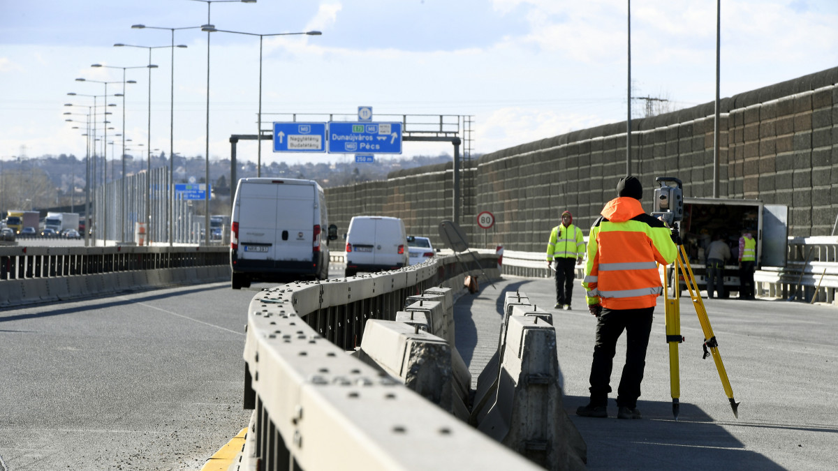 Munkások az M0-s autóút déli szakaszán, az M6-os kihajtójánál 2019. március 5-én. Április elejétől megkezdődik az M0 autóút déli szektorának felújítása, az 1-es főút és az M5-ös sztráda közötti szakaszon új forgalmi rend lép életbe.