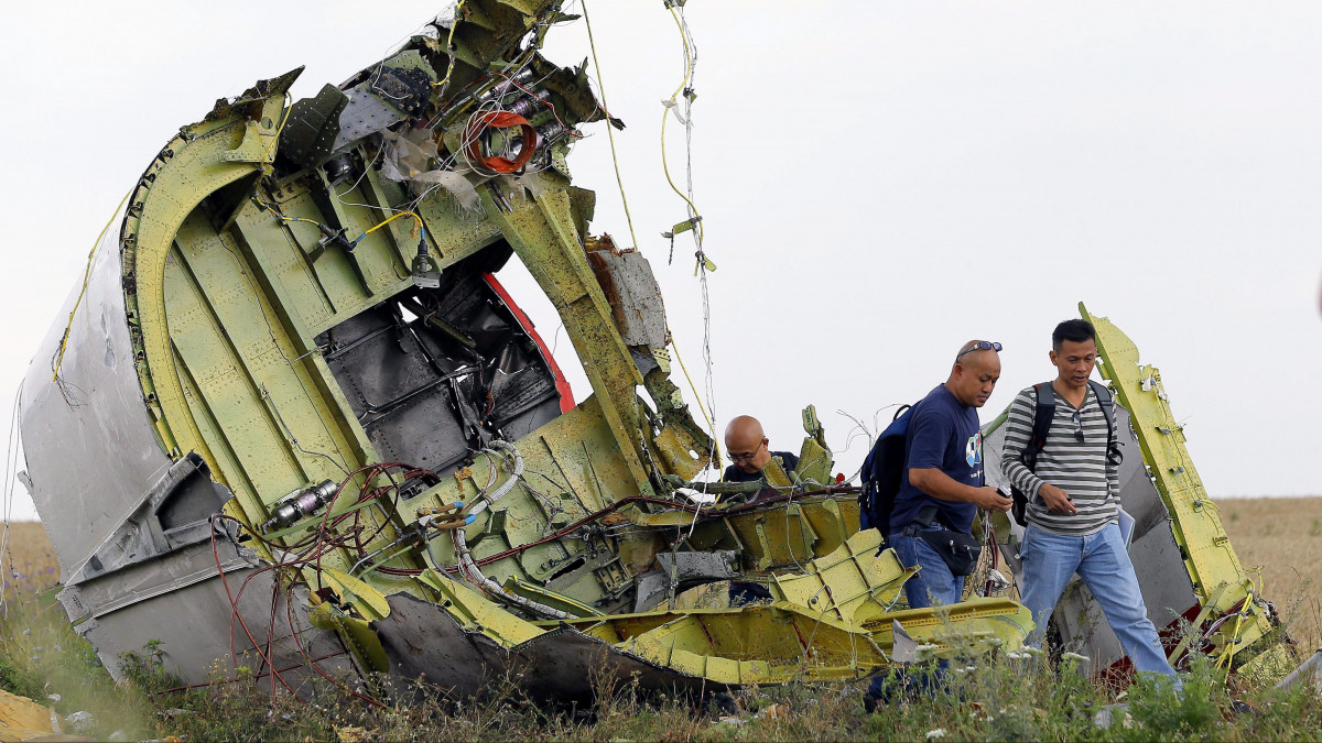 Harkiv, 2014. július 22.Malajzai szakértők a Malaysia Airlines légitársaság Boeing 777-es utasszállító repülőgépének egyik darabjánál a kelet-ukrajnai Hrabove város közelében 2014. július 22-én. A repülőgép 2014. július 17-én zuhant le az oroszbarát ukrajnai szakadárok uralta donyecki területen, a fedélzetén tartózkodó 298 személyből senki sem élte túl a katasztrófát. (MTI/EPA/Robert Ghement)