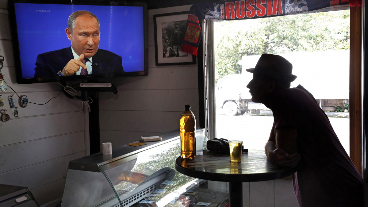 A lakossági kérdésekre élő adásban válaszoló Vlagyimir Putyin orosz elnököt nézi televízión egy podolszki vendéglátóhely vendége 2019. június 20-án.