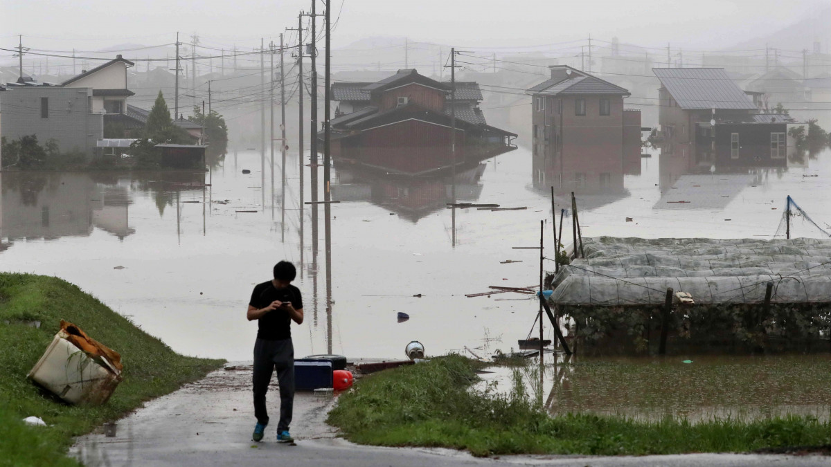 Kurasiki, 2018. július 8.Helybeli férfi vízben álló lakóházak közelében, a nyugat-japáni Okajama prefektúra Kurasiki városában 2018. július 8-án. A szigetország középső és nyugati részét sújtó árvíz eddig legkevesebb 64 ember halálát okozta, mintegy ötvenen eltűntek. A hatóságok a földcsuszamlás veszélye miatt legalább 2 millió embert szólítottak fel az otthonuk elhagyására. (MTI/EPA/JIJI Press)