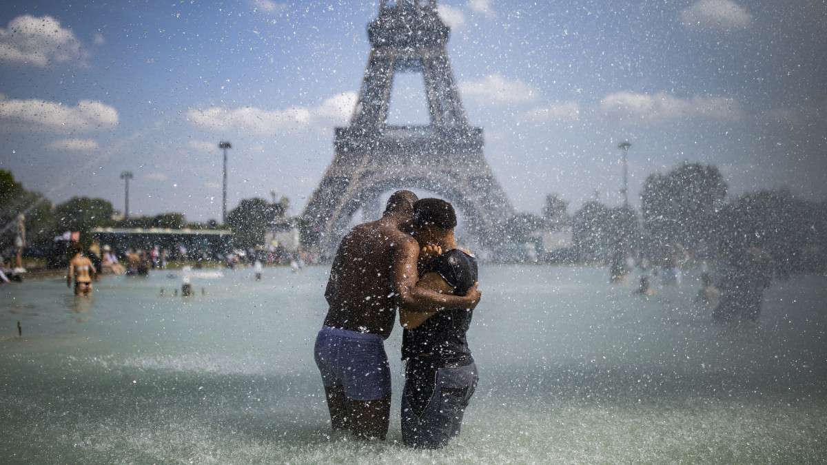 Egy pár hűsöl a párizsi Trocadéro tér szökőkútjában 2019. június 25-én. A francia fővárosban a hármas szintű hőhullámtervet léptették életbe, tizenhárom parkot tartanak nyitva éjszakánként is, hogy az emberek hűsölni tudjanak.