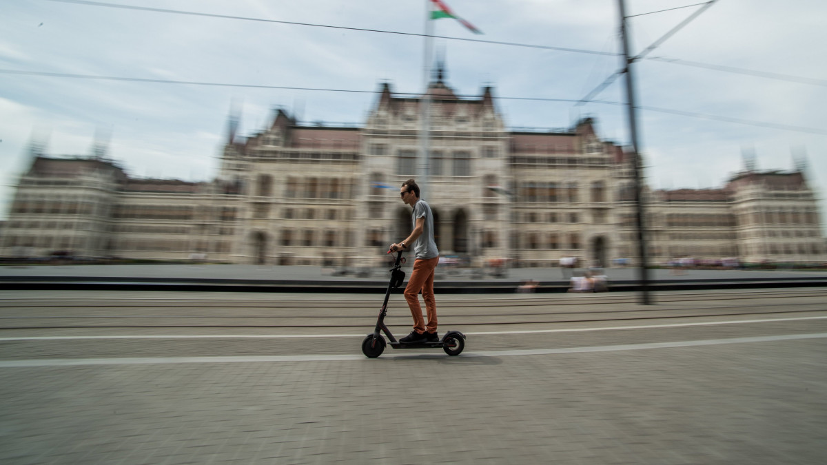 Férfi elektromos rollerrel Budapesten a Kossuth térnél 2018. május 30-án. Idén június közepétől tilos a segway (önegyensúlyozó, kétkerekű, elektromos meghajtású közlekedési eszköz), az elektromos kerékpár, az elektromos roller, az elektromos gördeszka, a hoverboard (önegyensúlyozó elektromos roller), a sörbike (négykerekű, többszemélyes kocsmabicikli) és a riksa használata az V. kerületi önkormányzat tulajdonában lévő gyalogutakon és gyalogos övezetekben.