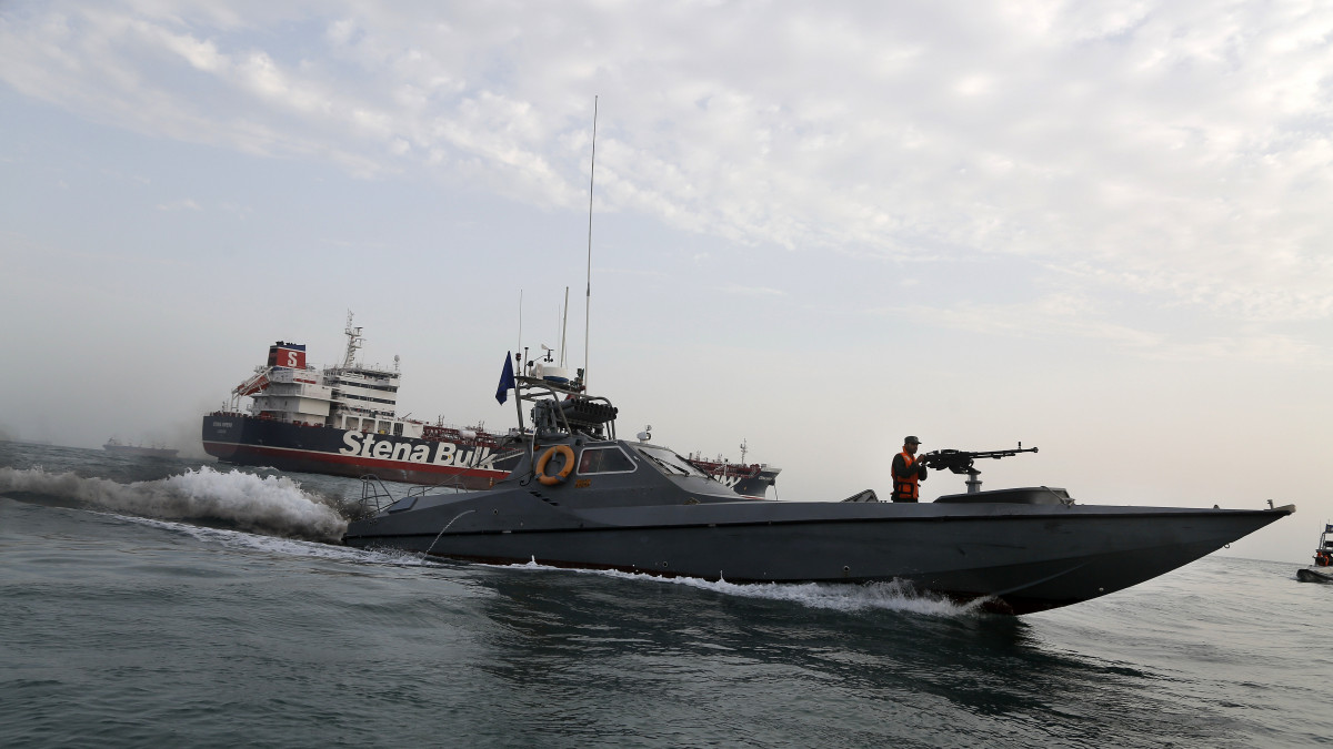 Az iráni Forradalmi Gárda motorcsónakja a Stena Impero brit tartályhajónál, a Hormuzi-szorosban fekvő dél-iráni Bandar-Abbász kikötőváros vizein 2019. július 21, két nappal az után, hogy az iráni hadsereg szervezeti egysége lefoglalta a brit tankert a Perzsa-öbölt az Ománi-öböllel összekötő tengerszorosban. Az iráni alkotmányvédelmi tanács szerint a Stena Impero lefoglalása az iráni hatóságok jogszerű válasza arra, hogy a brit tengerészgyalogság július elején Gibraltárnál lefoglalta a Grace 1 iráni tartályhajót.