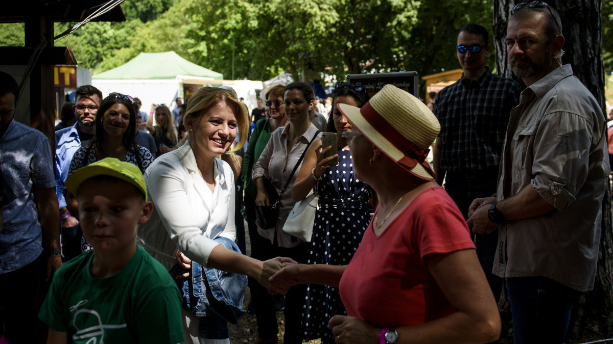 Zuzana Caputová szlovák köztársasági elnök (b) kezet fog egy résztvevővel a Gombaszögi Nyári Táborban a felvidéki Szalóc közelében 2019. július 17-én.
