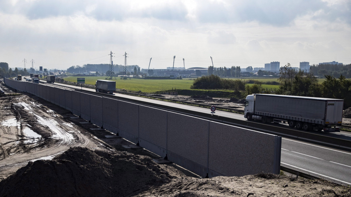 Calais, 2016. október 25.Egy kamion halad el a kikötőbe vezető út mentén épülő négy méter magas fal mellett az észak-franciaországi Calais-ban 2016. október 25-én, a Dzsungelnek nevezett migránstábor felszámolásának második napján. Az egy kilométer hosszú, az út két oldalára tervezett fallal az illegális bevándorlókat akarják megakadályozni abban, hogy a Csatorna-alagúton keresztül Nagy-Britanniába tartó teherautókra felkapaszkodhassanak.  (MTI/EPA/Etienne Laurent)